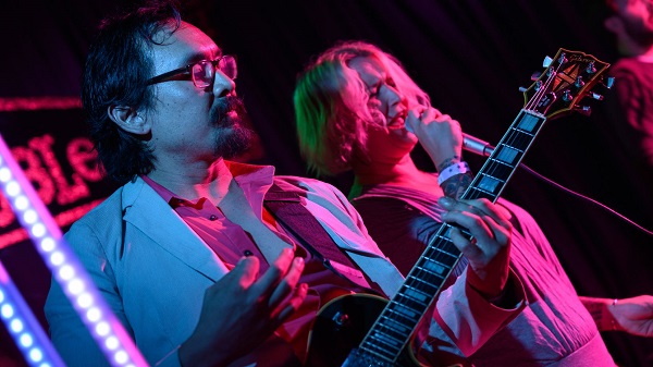 Female Vocalist Performing During A Concert White Male Lead Guitarist On His Track.